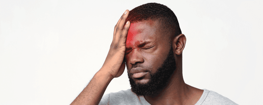 Man with one hand to his head in pain.