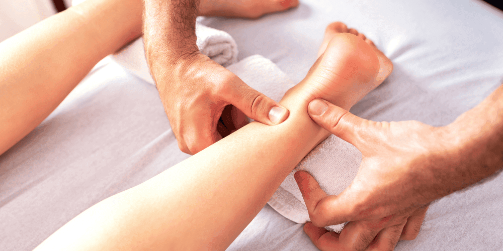 Woman on a massage table getting her ankle massaged.