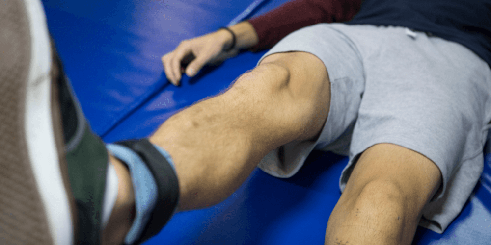 Man in a gym doing a knee exercise.