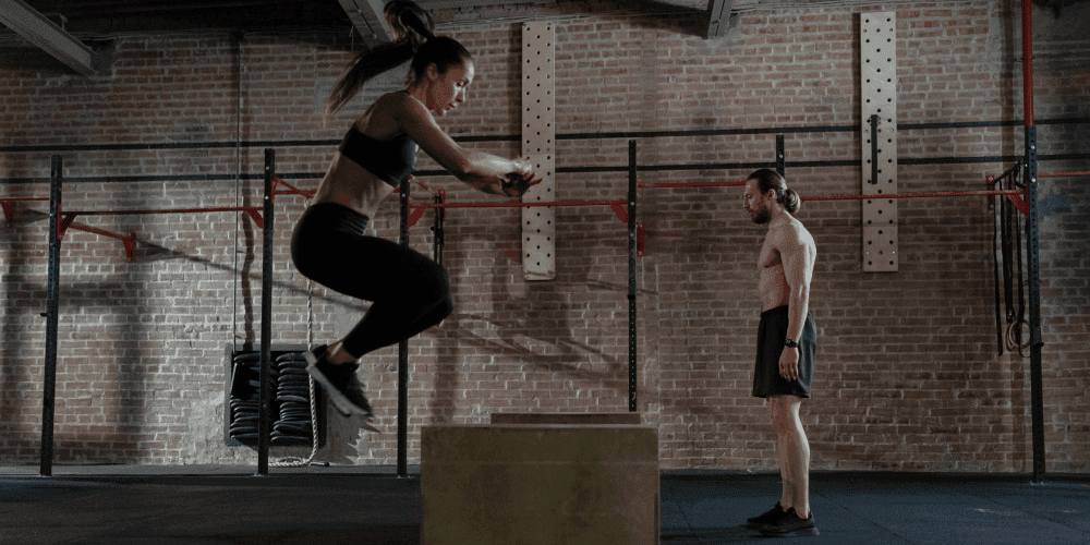 Woman doing box jumps in a crossfit gym.